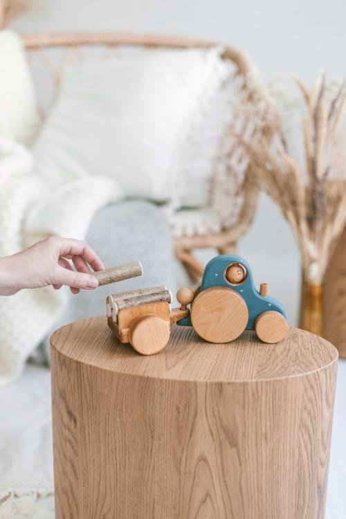 Kinder spielen mit dem Spielzeug Traktor aus Holz – fördert motorische Entwicklung